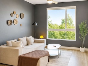 A modern living room with a grey wall, a large window, a sofa, a coffee table, and decorative wall art.