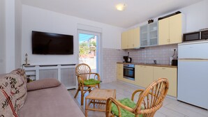 Un espacio habitable compacto con un sofá, dos sillas, un televisor, una cocina con armarios, un horno y un microondas.