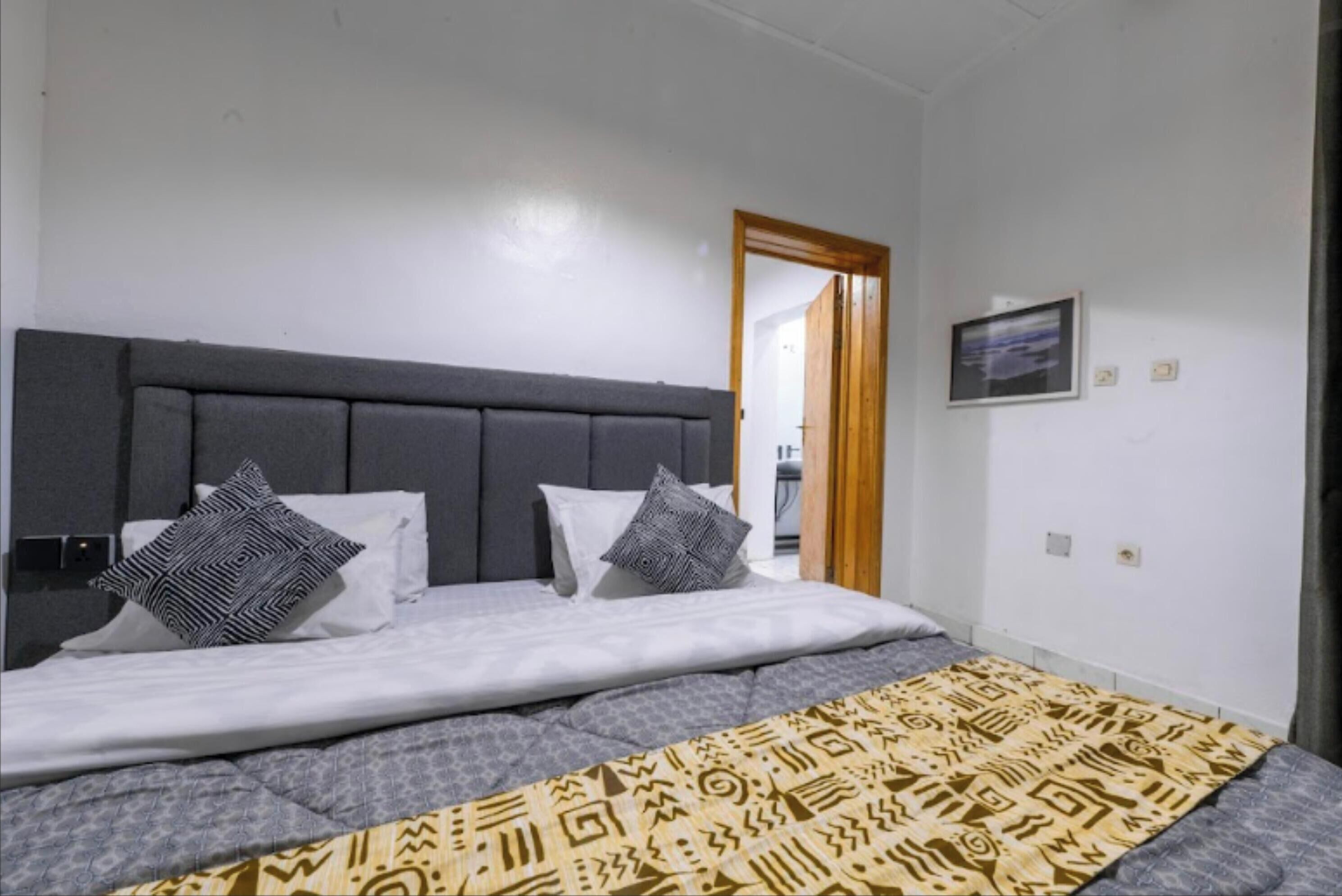 Ein Schlafzimmer mit einem großen Bett, einer Kopfteil und einer gesteppten Bettdecke.
