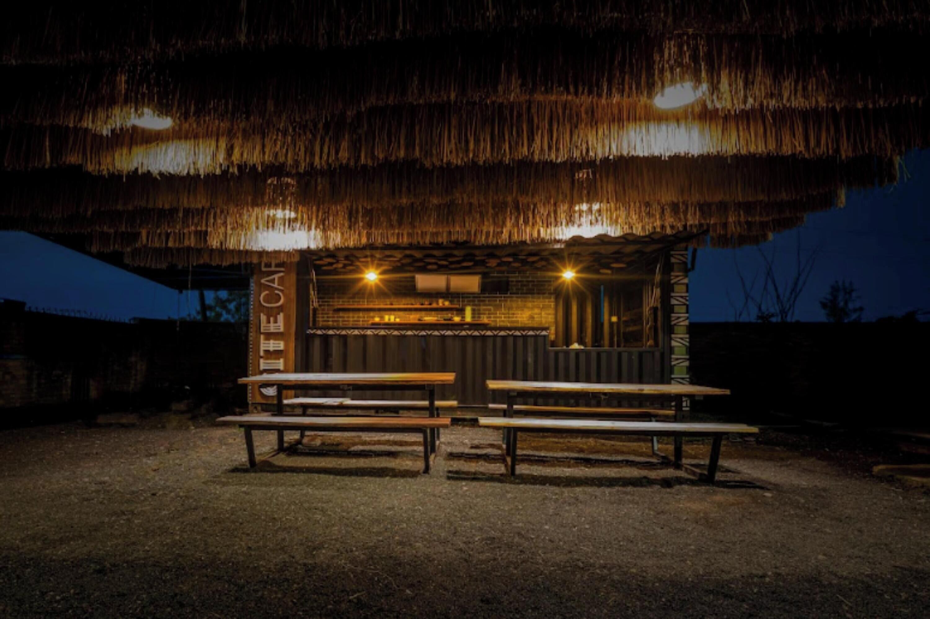 Un espacio de estar al aire libre rústico con bancos de madera y una estructura de techo de paja.
