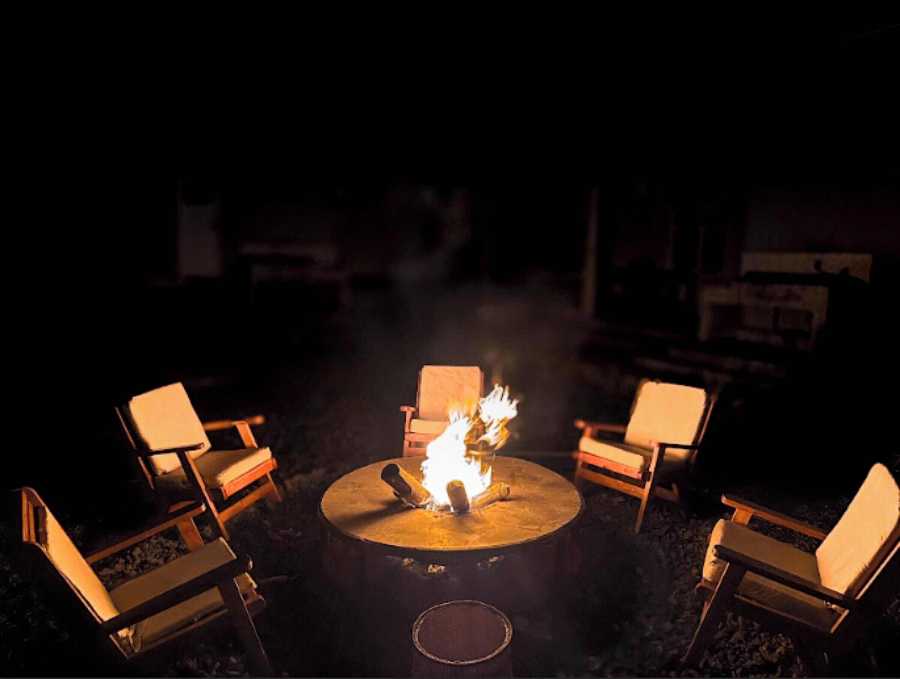 A circular fire pit with chairs around it, set outdoors at night.