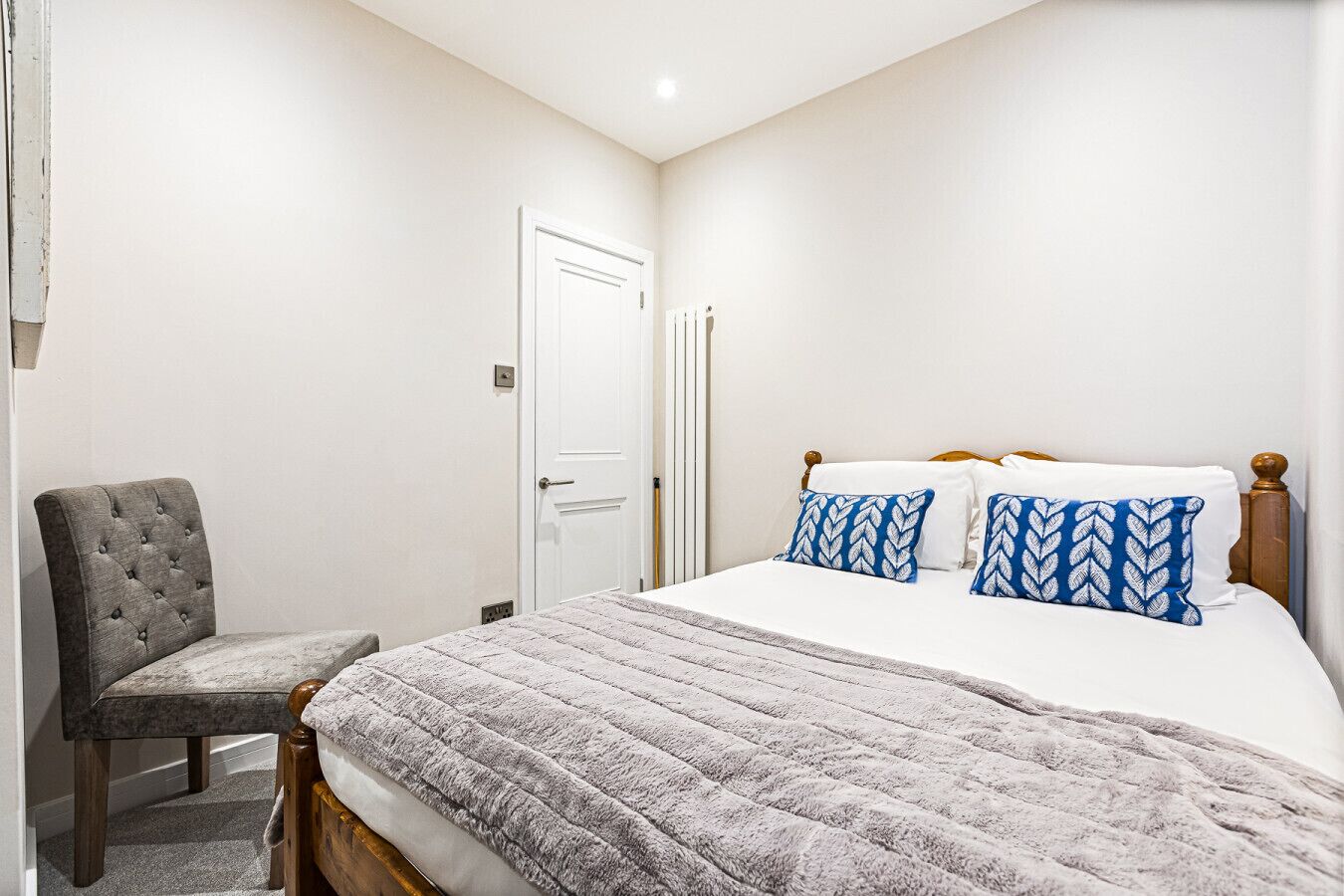 Un dormitorio con una cama, una silla y una puerta.