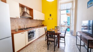A kitchen with white cabinets, a stove, and a dining area with a table and chairs.
