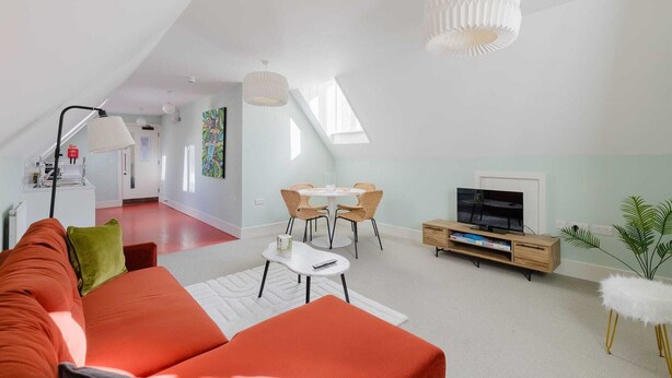 A modern living room with a sofa, TV, dining table, and chairs.