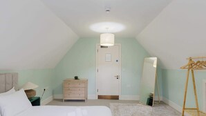 A bedroom with a bed, dresser, mirror, and a wooden ladder.