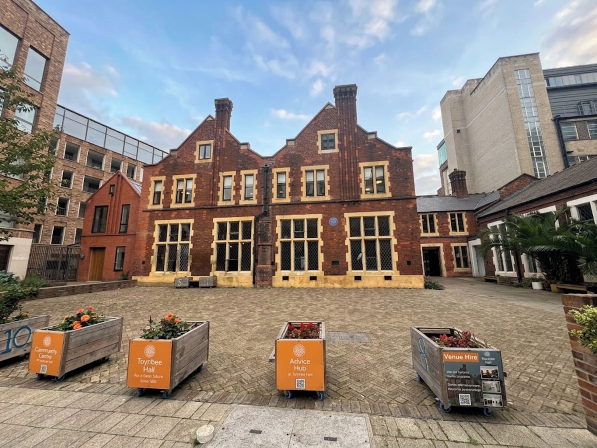 Un bâtiment en briques doté de nombreuses fenêtres et d’une cour intérieure agrémentée de jardinières.