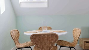 A round table with four wicker chairs, a clear vase, and a light blue wall.