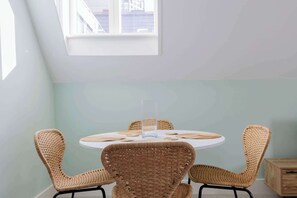 A round table with four wicker chairs, a clear vase, and a light blue wall. - Spacious 3BD Flat in Historic Building Shoreditch (Greater London)