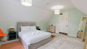 A bedroom with a bed, bedside tables, a chair, a wardrobe, and a mirror. - Spacious 3BD Flat in Historic Building Shoreditch (Greater London)