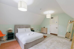 A bedroom with a bed, bedside tables, a chair, a wardrobe, and a mirror.