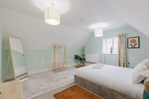 A bedroom with a bed, a mirror, a radiator, a window with curtains, and a plant.