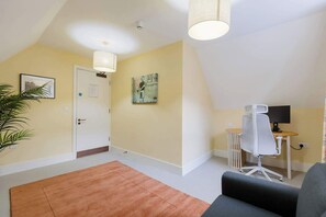 A room with a door, a painting, a desk with a chair, a plant, and a large window. - Spacious 3BD Flat in Historic Building Shoreditch (Greater London)