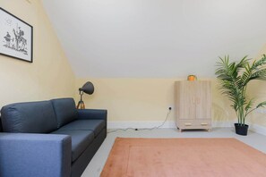 A room with a sofa, a lamp, a cabinet, a potted plant, and a framed picture on the wall.