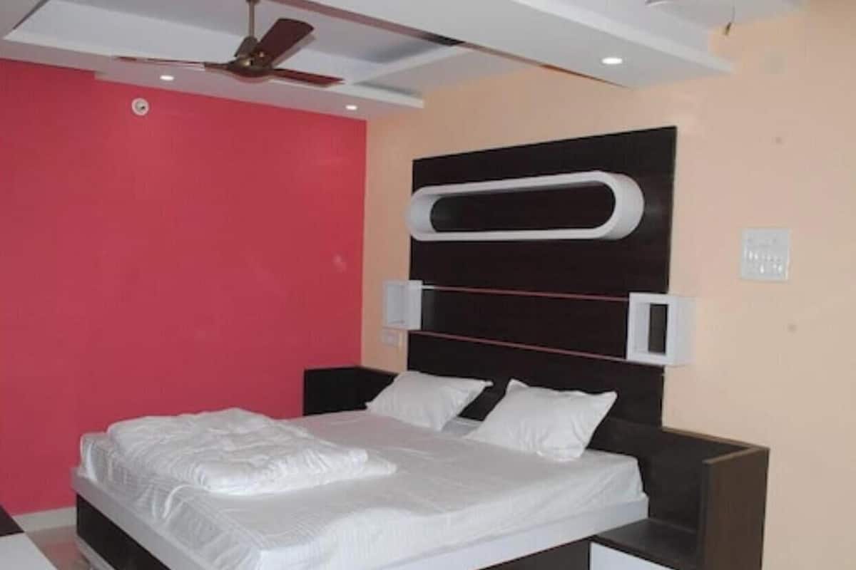 Quarto moderno com cama, mesas de cabeceira e ventoinha no teto.