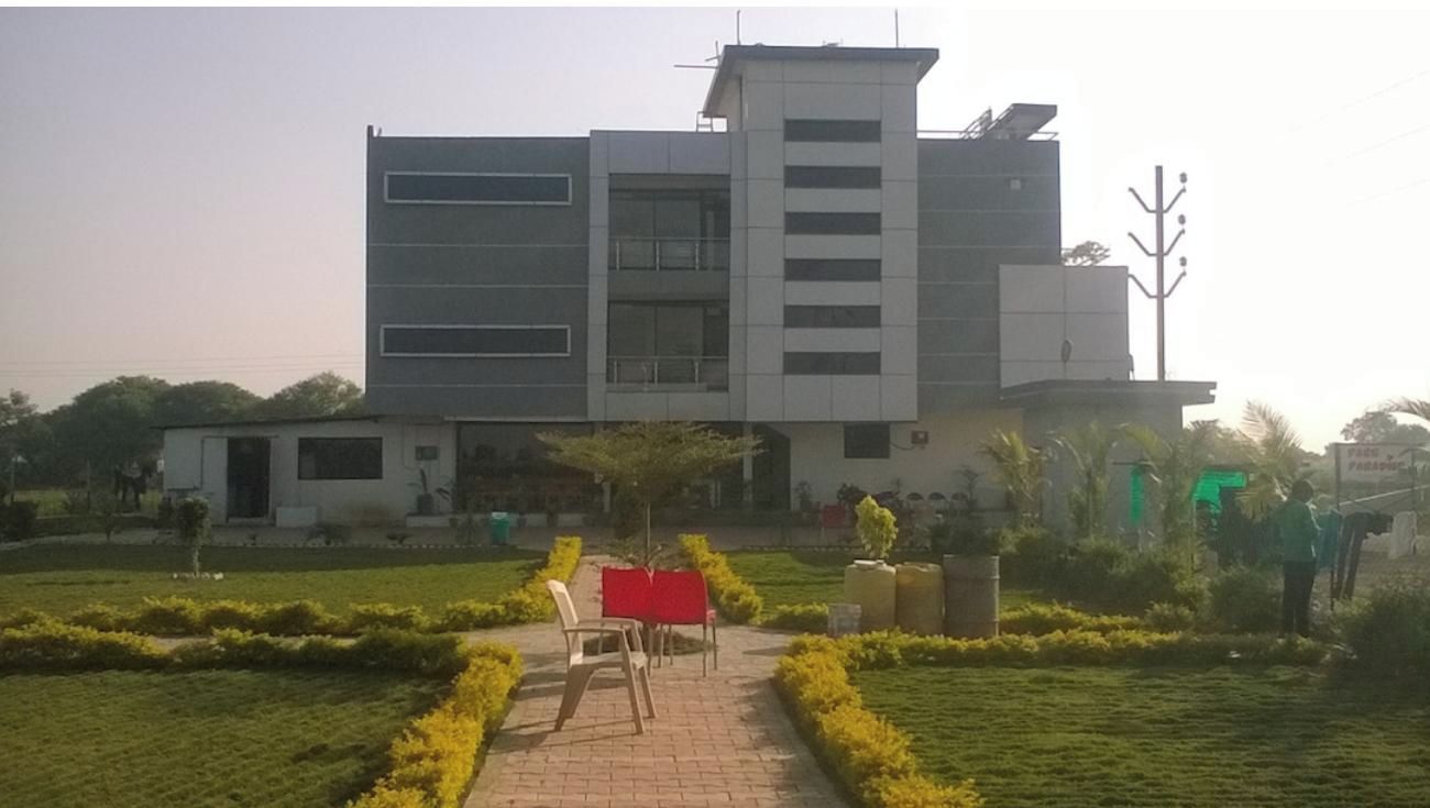 A modern building with a central courtyard, a flagpole, and a small seating area with chairs and a table.