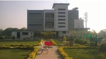 A modern building with a central courtyard, a flagpole, and a small seating area with chairs and a table.