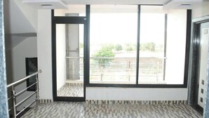 Ein Zimmer mit großem Fenster, einer Tür und Fliesenboden.