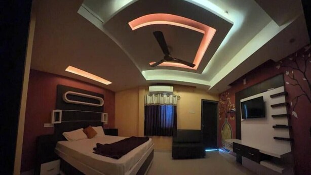 Ein modernes Schlafzimmer mit einem Bett, einem Deckenventilator und einem an der Wand montierten Fernseher.