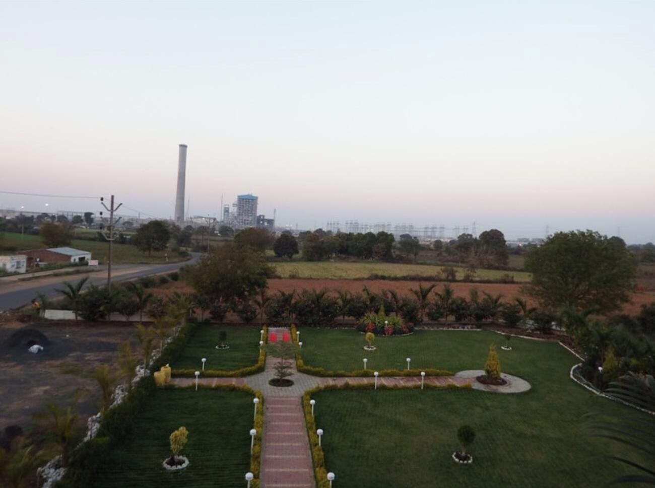 A landscaped garden with pathways, a central walkway, and a tall structure in the background.