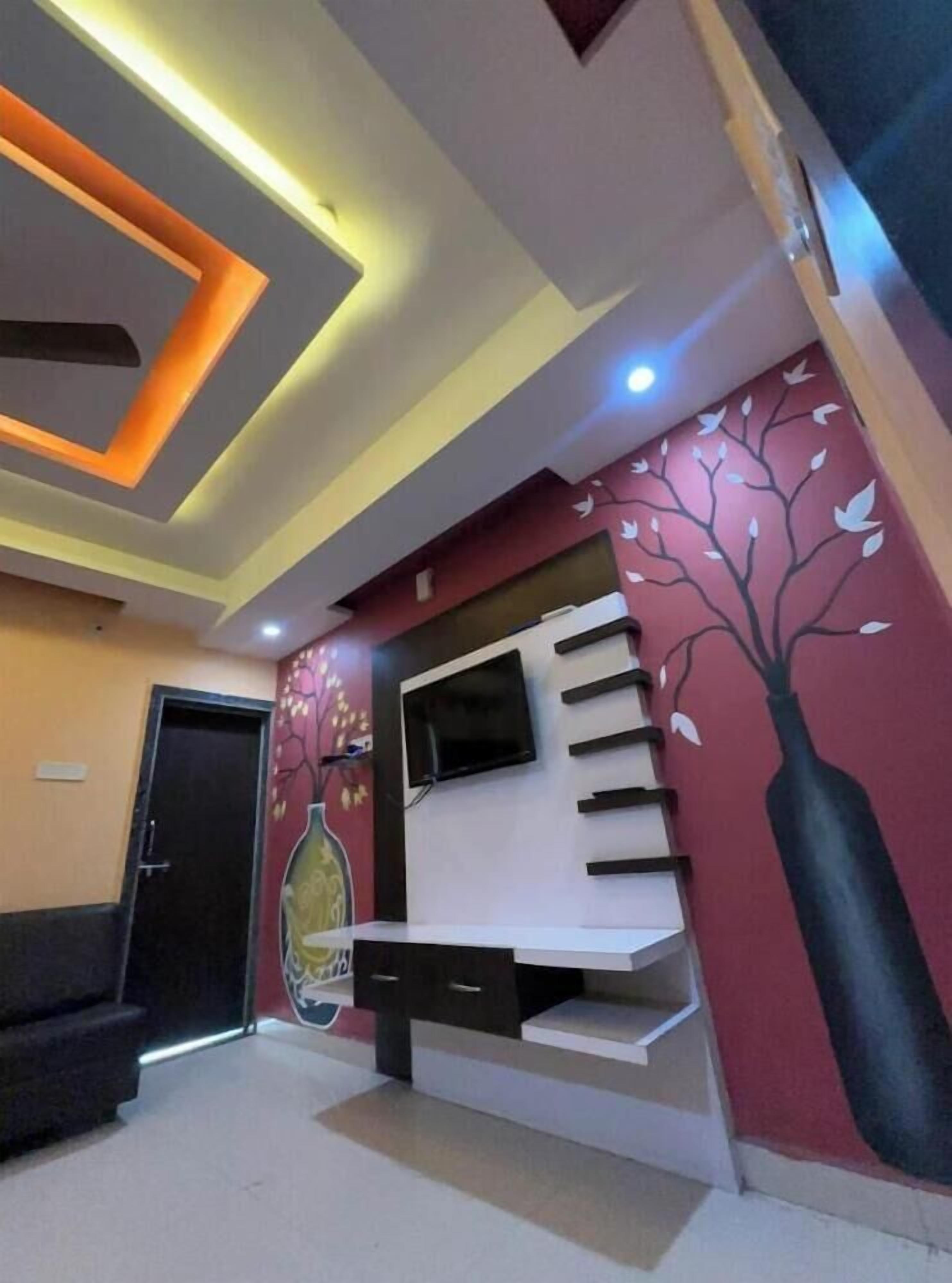 Un intérieur moderne agrémenté d’un escalier, d’un téléviseur à écran plat et d’une fresque murale représentant un arbre décoratif.