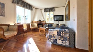 Ein gemütliches Wohnzimmer mit Holzboden, einer Sofagarnitur, einem Kamin und einem Fernseher.