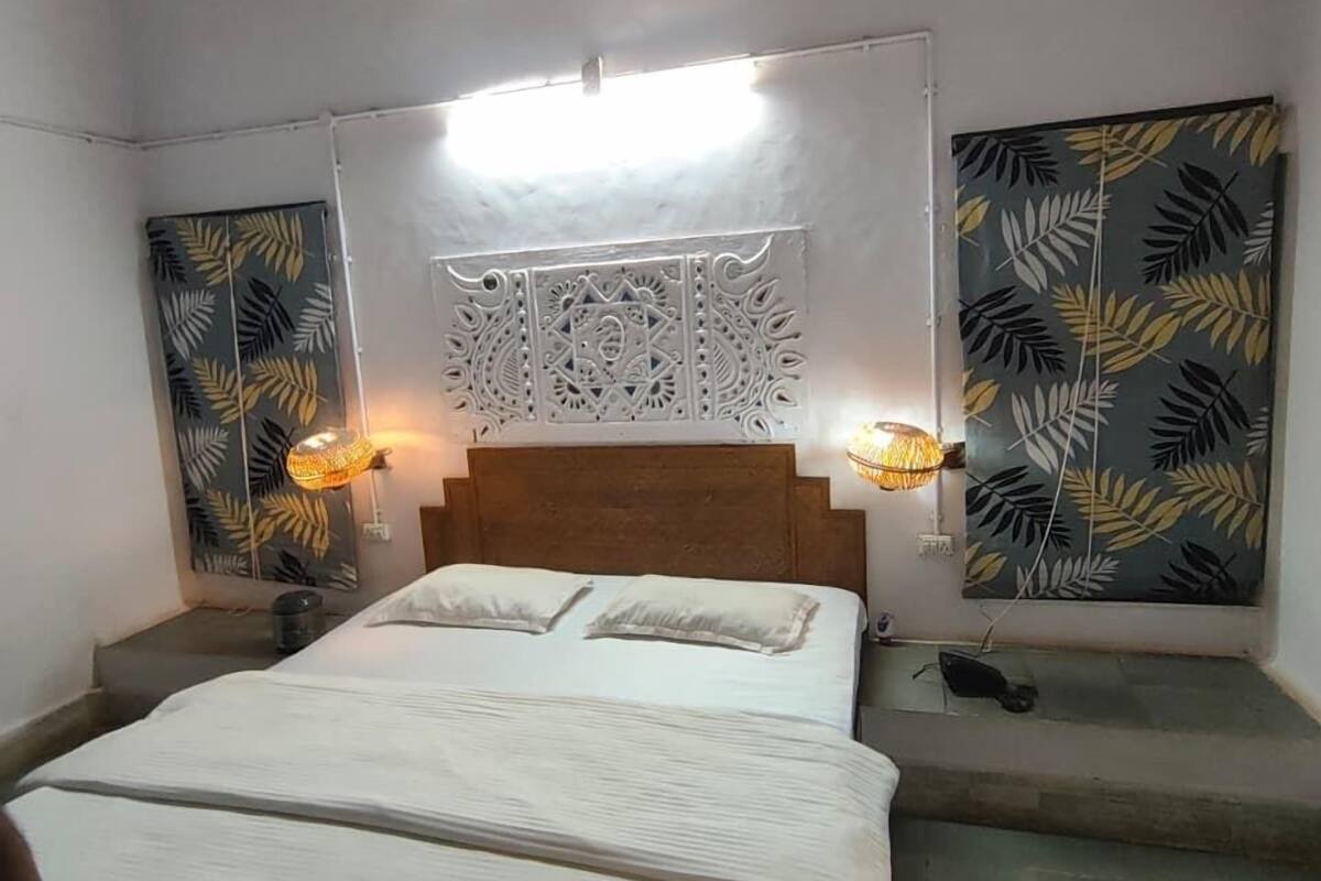 A bedroom with a bed, two bedside lamps, a ceiling light, and decorative wall panels.