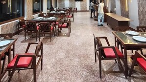 Un restaurant spacieux doté de nombreuses tables et chaises, de ventilateurs de plafond et d’un éclairage moderne.