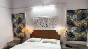 Une chambre à coucher comprenant un lit, deux tables de chevet, une tête de lit décorative et des œuvres d’art murales.