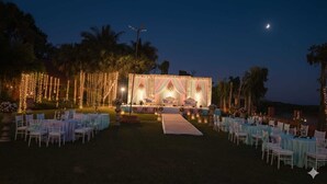 Un lieu de réception en plein air pour les mariages, équipé d’une scène, de tables, de chaises et de guirlandes lumineuses.
