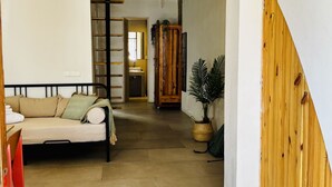 Une pièce comprenant un lit, une armoire en bois, une plante et un escalier menant à une autre pièce.
