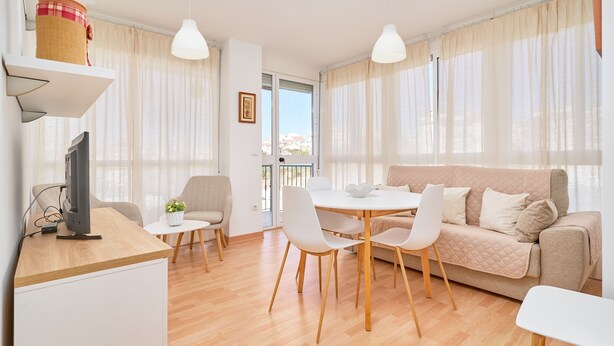 Un salon moderne comprenant un canapé, une table à manger, des chaises, un téléviseur et une fenêtre avec des rideaux.