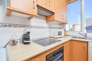 A modern kitchen with wooden cabinets, a built-in microwave, a coffee maker, and a gas stove.