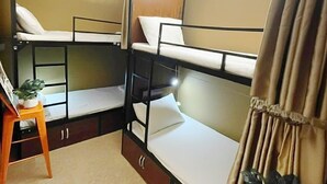 A compact room with bunk beds, a small table with a plant, and a curtain. - NOOK INN OLD QUARTER HANOI (Hanoi)
