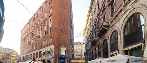 Una calle con edificios, entre ellos una pizzería y un restaurante.
