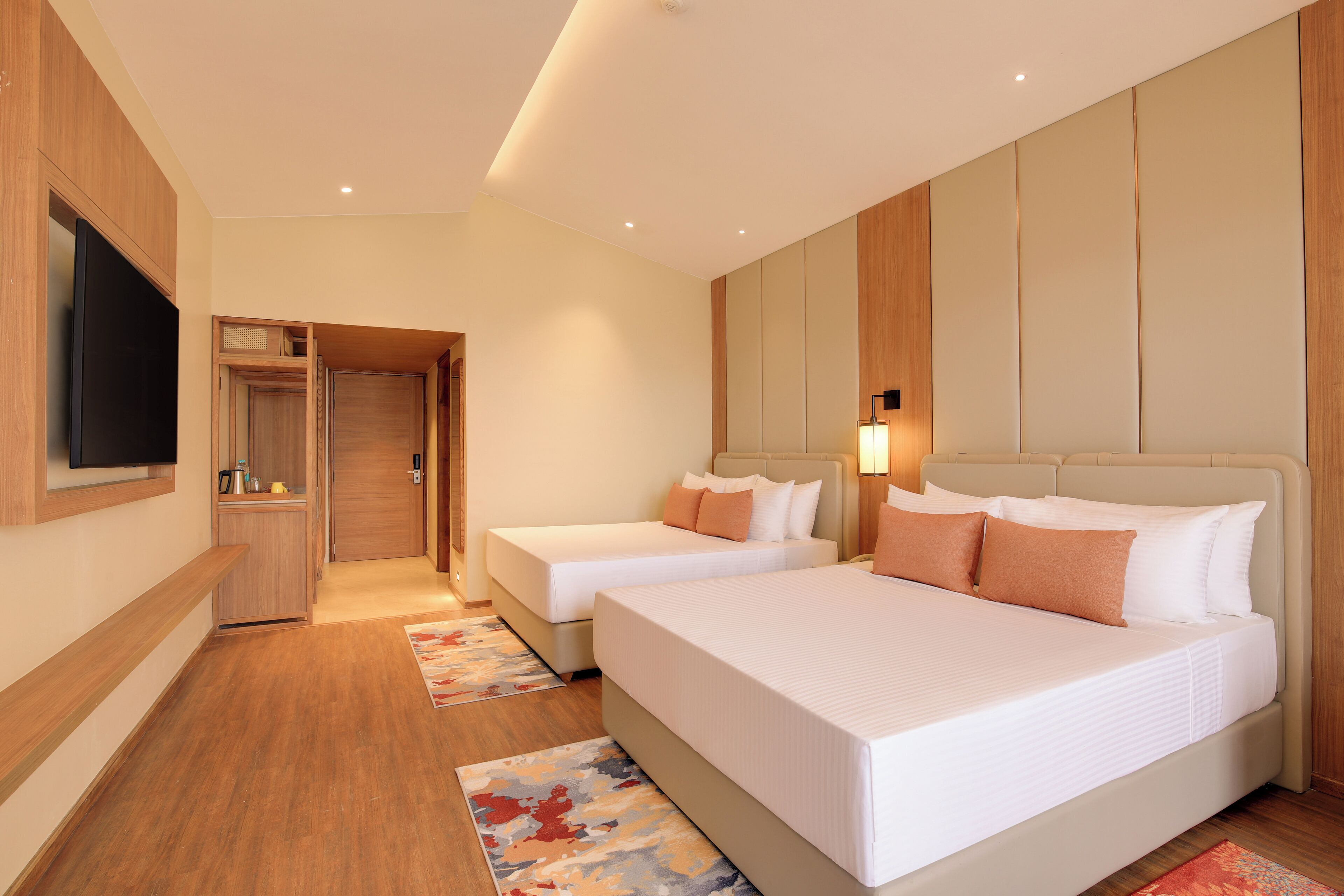 Ein Hotelzimmer mit zwei Betten, einem Fernseher, einer Minibar und Holzboden.