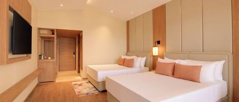 A hotel room with two beds, a TV, a minibar, and a wooden floor.