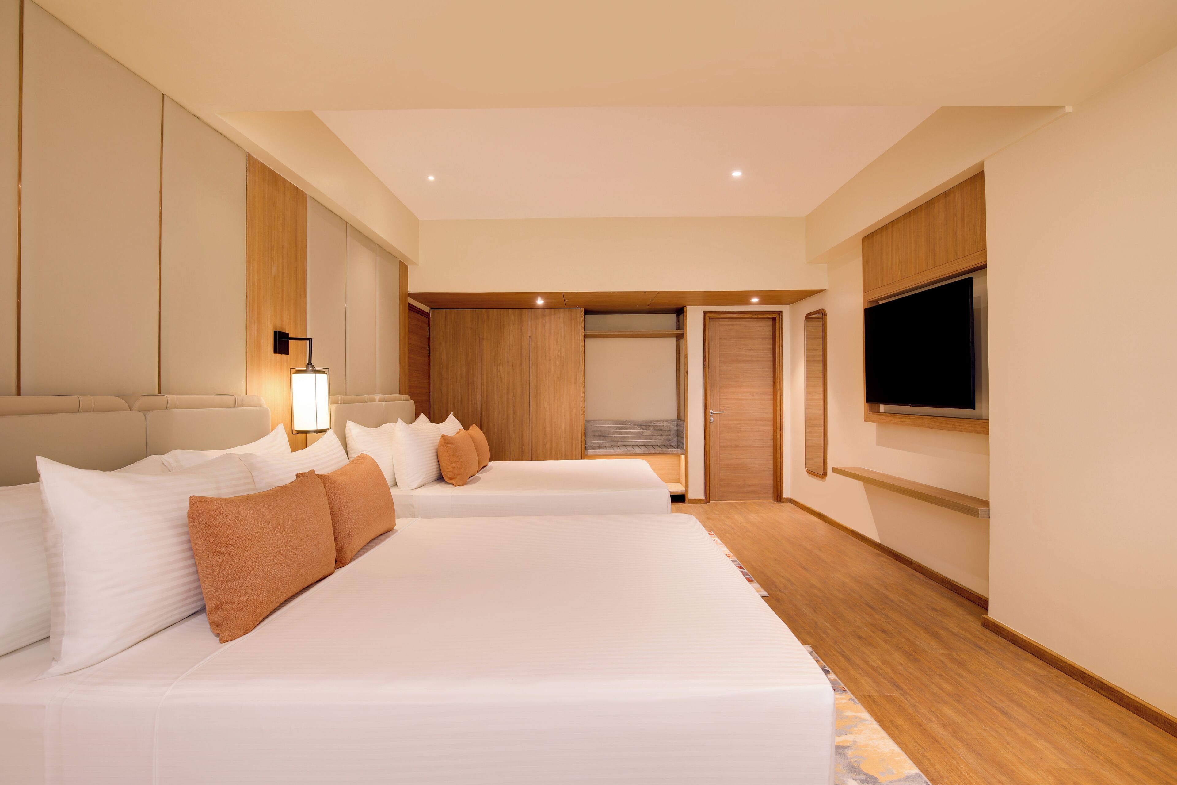 A modern hotel room with two beds, a TV, and a wooden wardrobe.