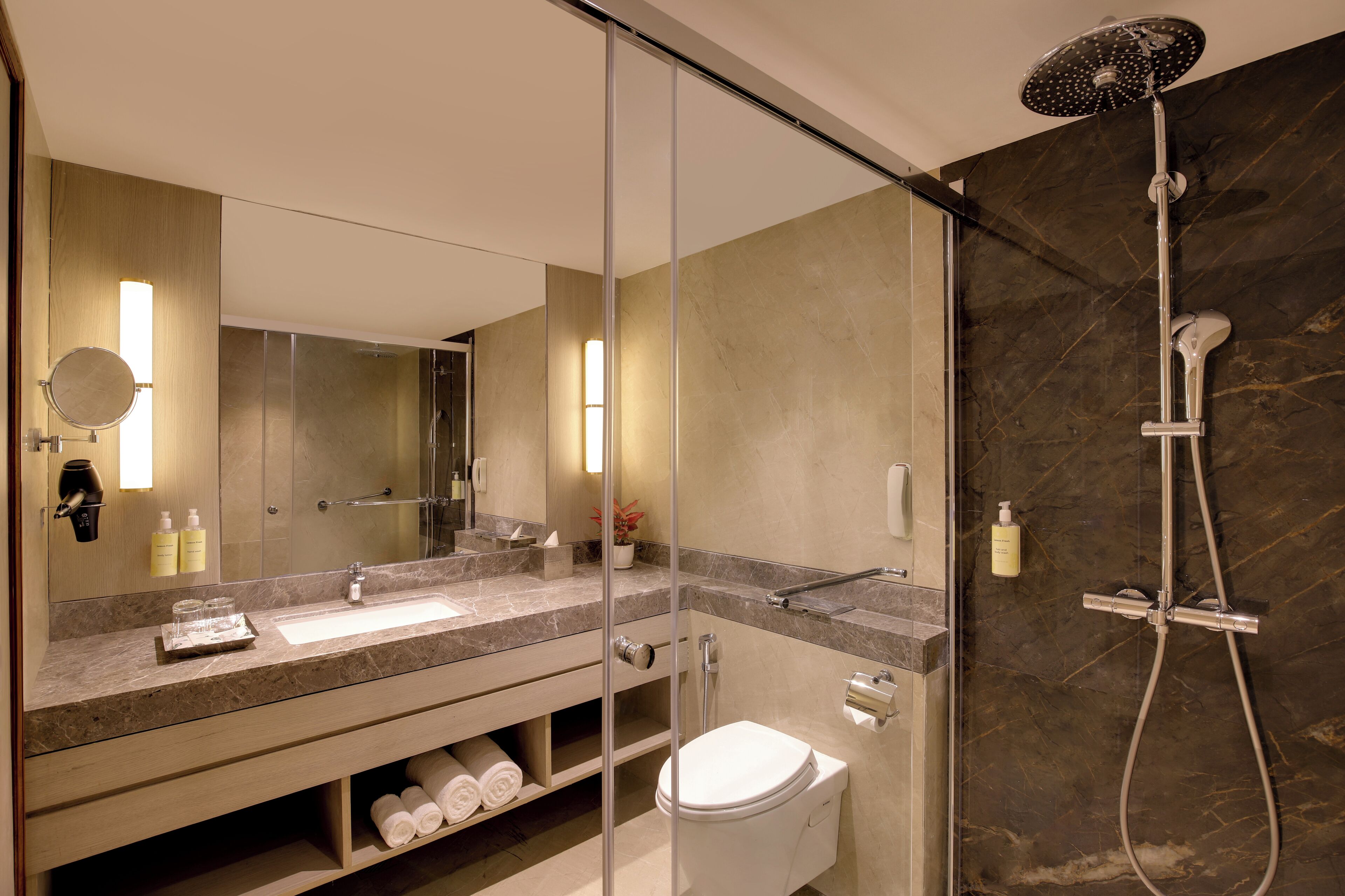 Un baño moderno con cabina de ducha de vidrio, lavamanos con encimera de mármol y retrete.