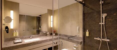 Un baño moderno con cabina de ducha de vidrio, lavamanos con encimera de mármol y retrete.