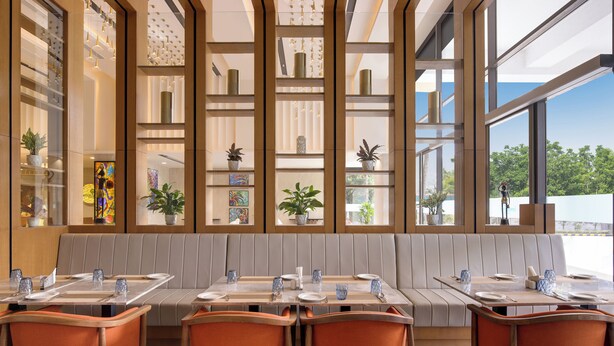 Een modern restaurant met een lange balie, comfortabele zitplaatsen en grote ramen met uitzicht op het omliggende landschap.