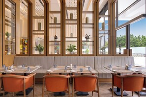 A modern restaurant with a long counter, cushioned seating, and large windows offering a view of the outdoors. - Lemon Tree Hotel Mall of Dehradun (Dehradun)