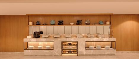 A modern kitchen with marble countertops, a wooden wall, and various kitchenware displayed on shelves.