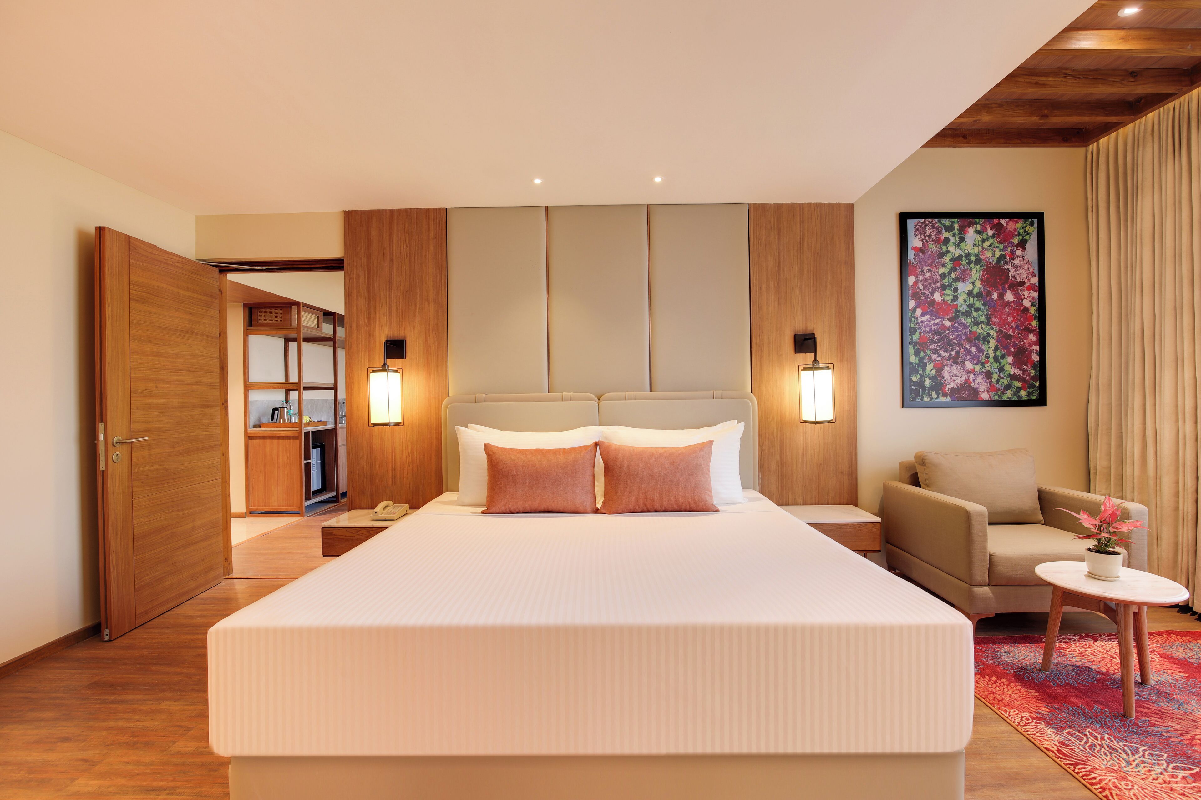 A hotel room with a large bed, a sofa, a small table, and a painting on the wall.