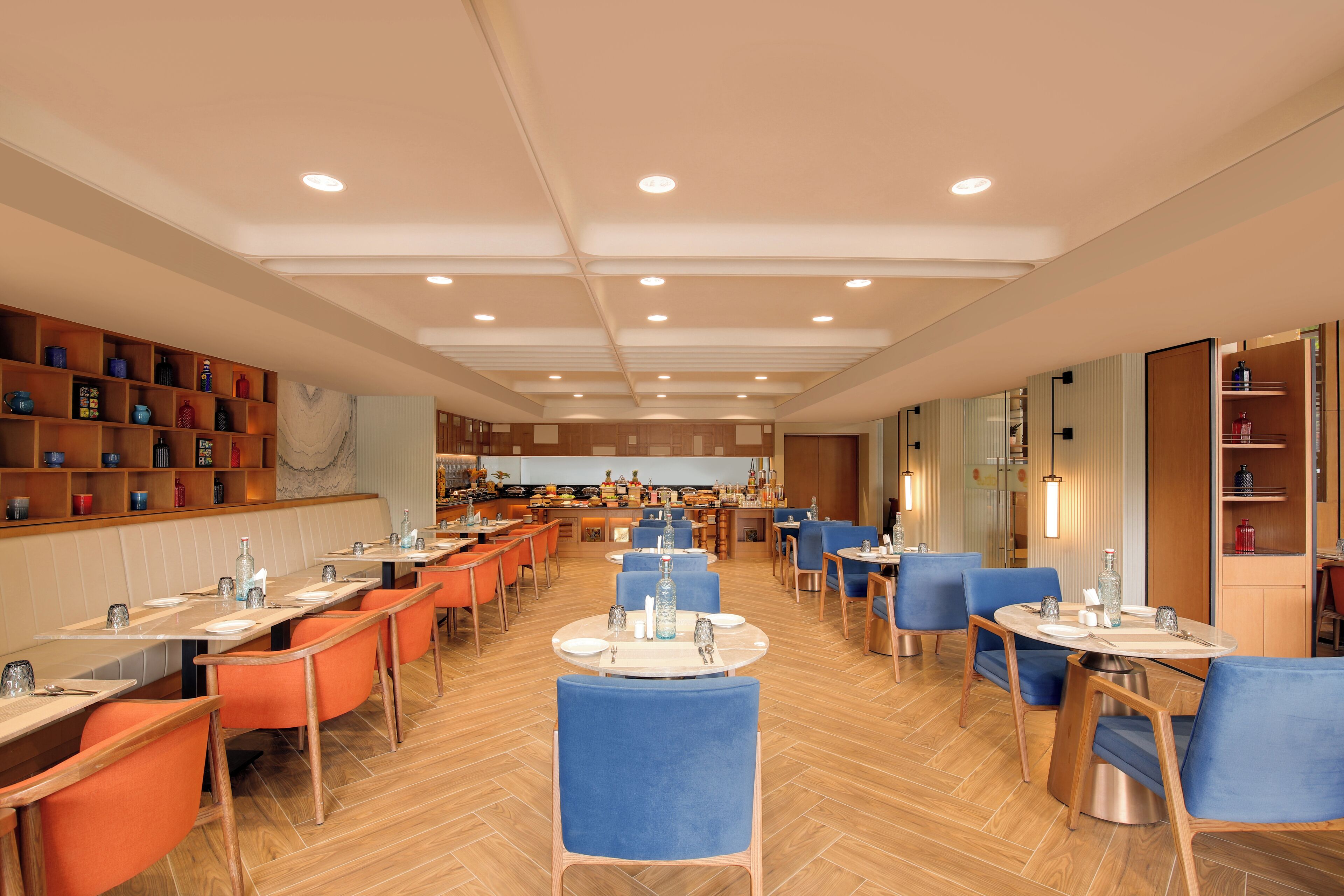 Un restaurant spacieux doté de nombreuses tables et chaises, offrant différents types de sièges, et bénéficiant d’un éclairage intérieur agréable.