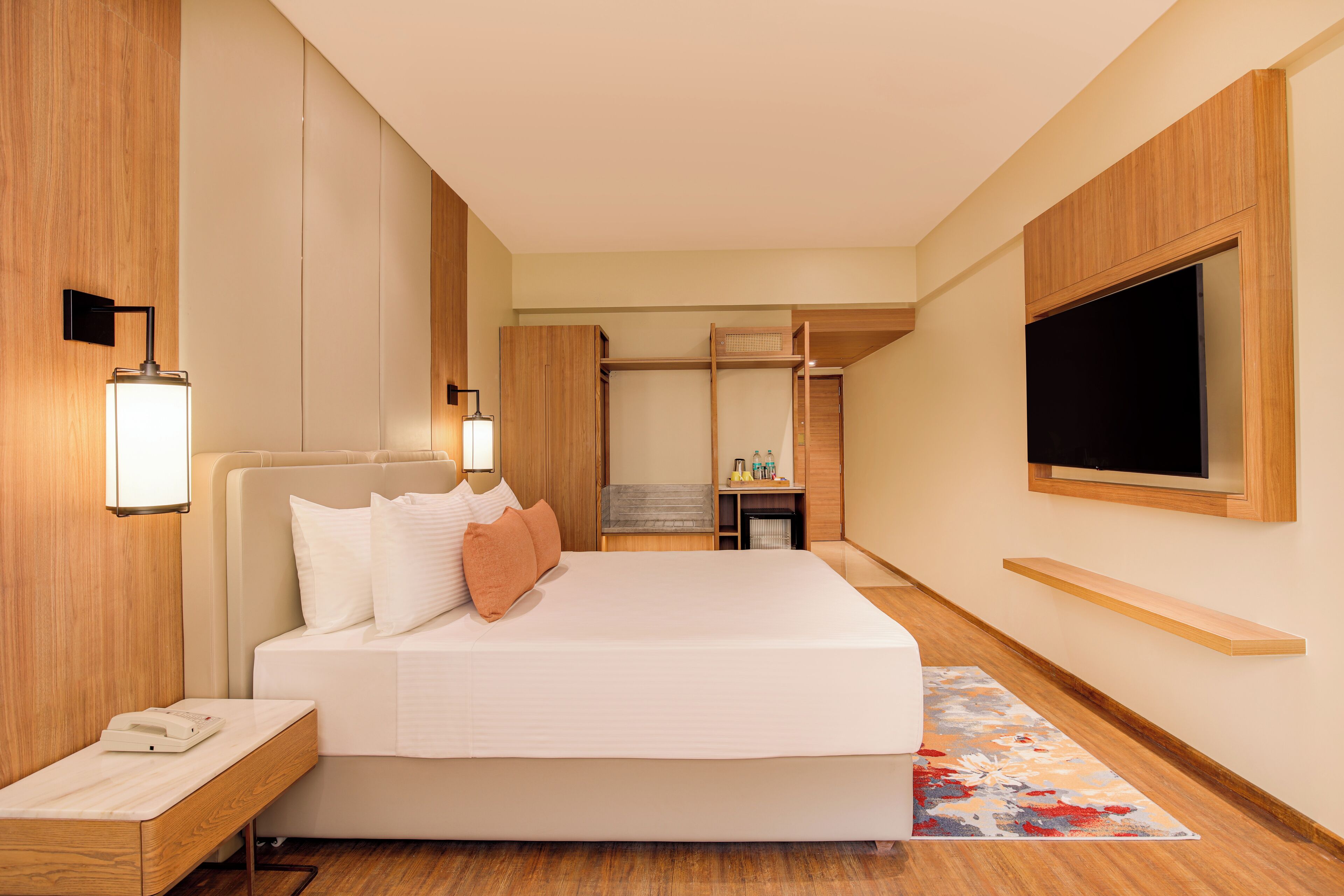 Une chambre d’hôtel moderne avec un grand lit, des lampes de chevet, un téléviseur à écran plat et un plancher en bois.