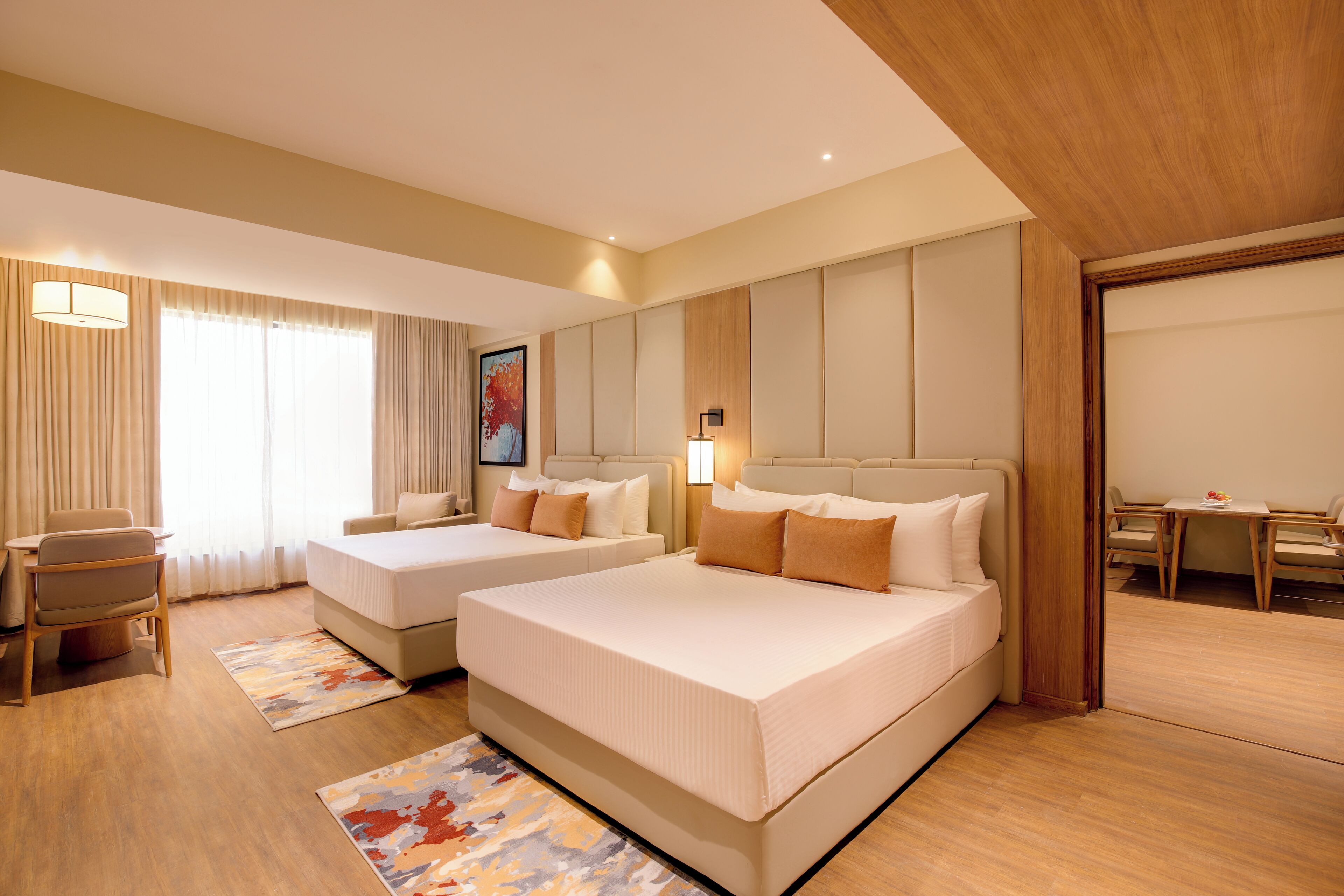 A hotel room with two beds, a desk, and a chair.