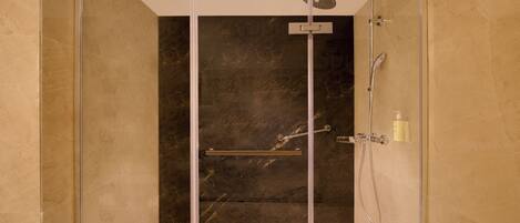 A modern shower with a glass door, a handheld showerhead, and a handheld shower attachment.