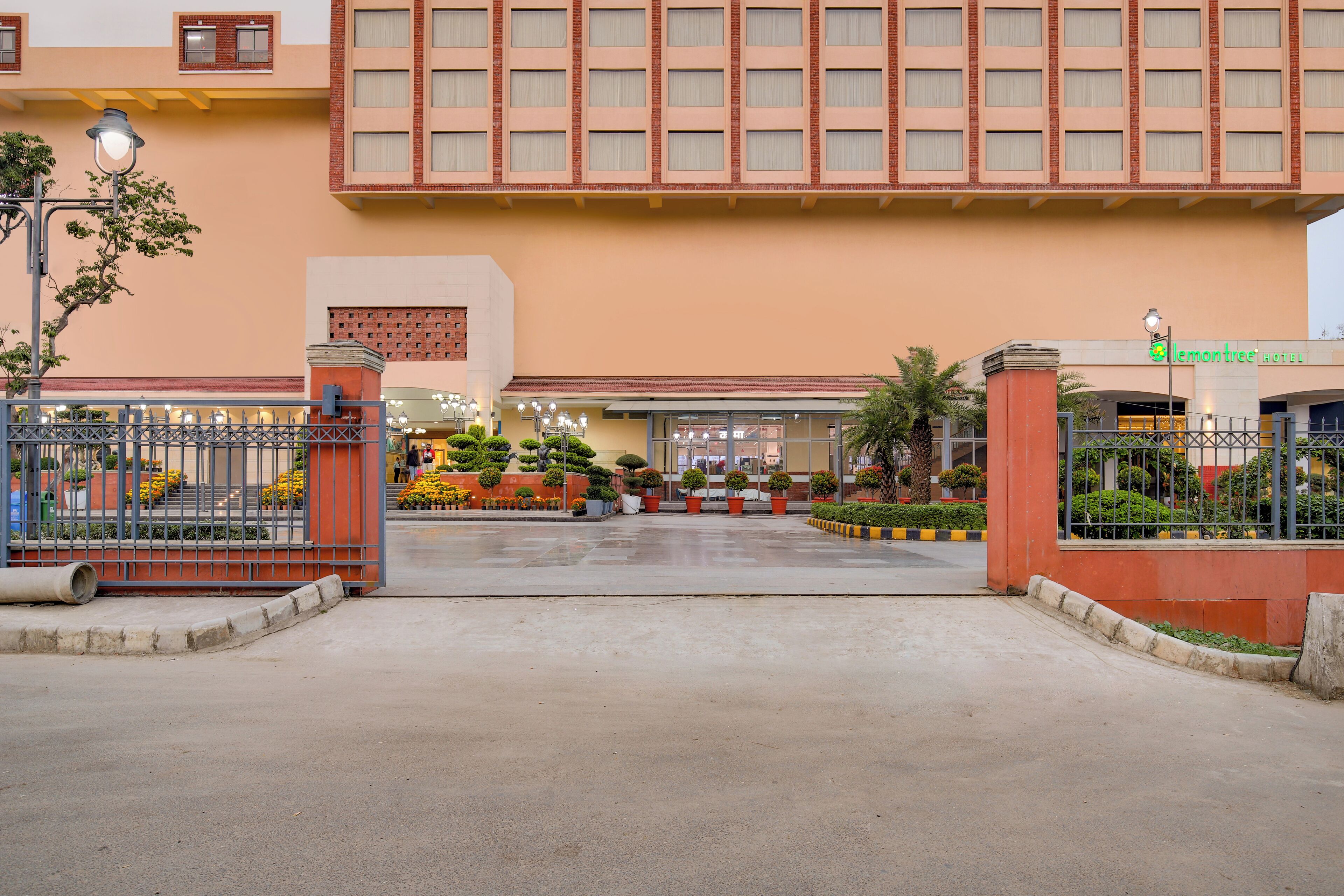 A hotel entrance with a large brick facade, a gated driveway, and well-maintained landscaping.