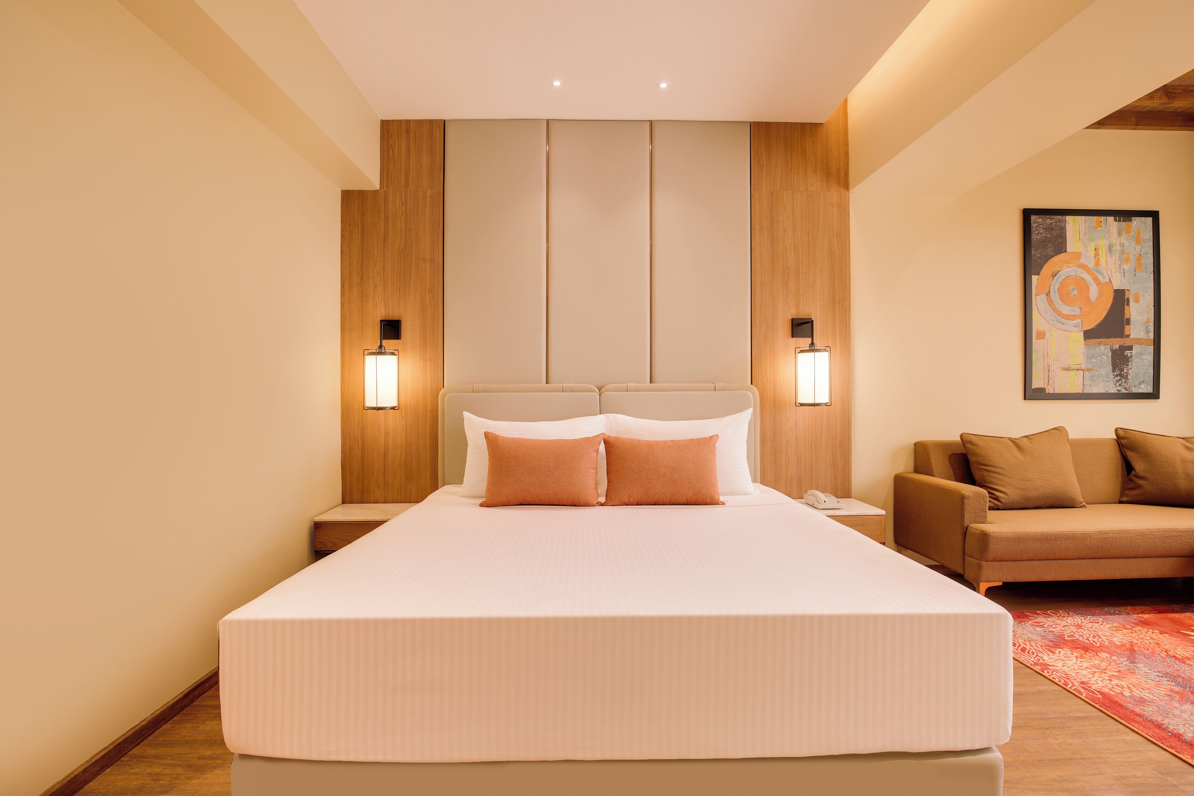 Ein modernes Hotelzimmer mit einem großen Bett, einer Couch und einem Gemälde an der Wand.