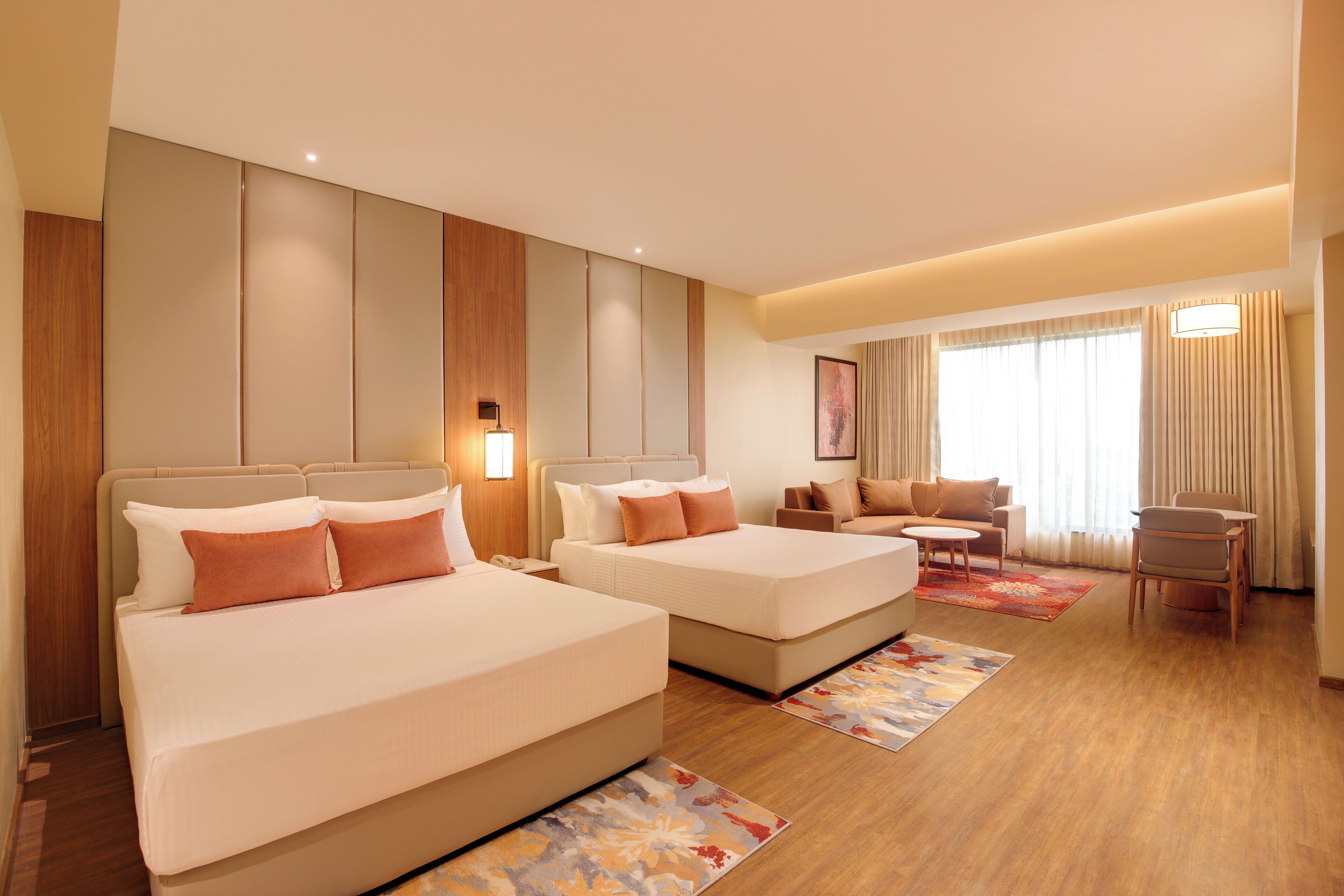 A hotel room with two beds, a sofa, a small table, and a chair.